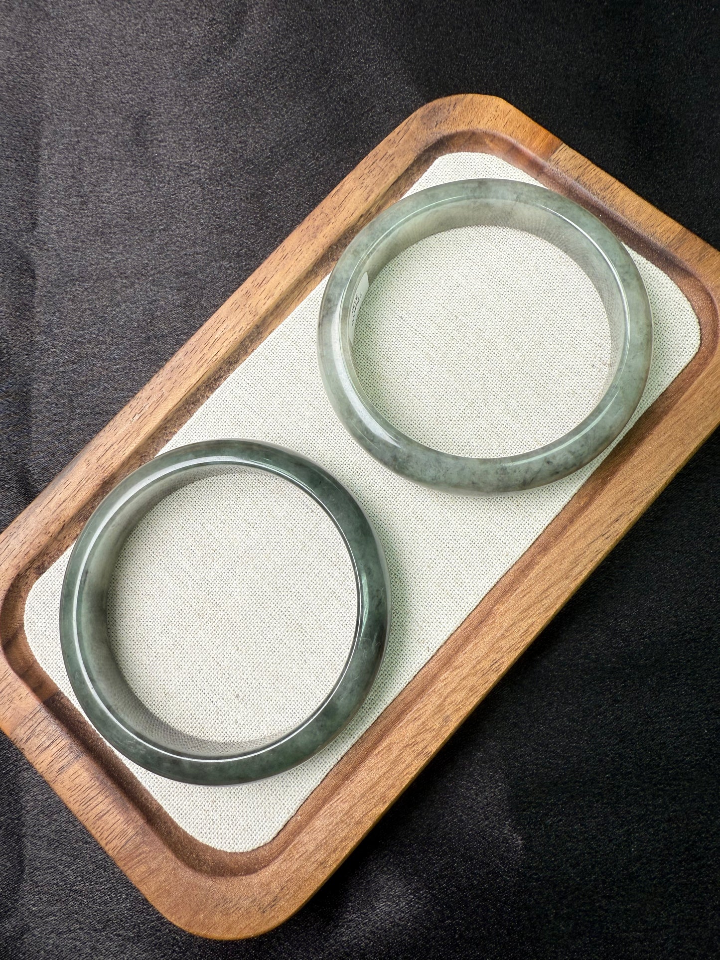 Two Black Wujin Jadeite(黑乌鸡翡翠)on a wooden tray with a black background