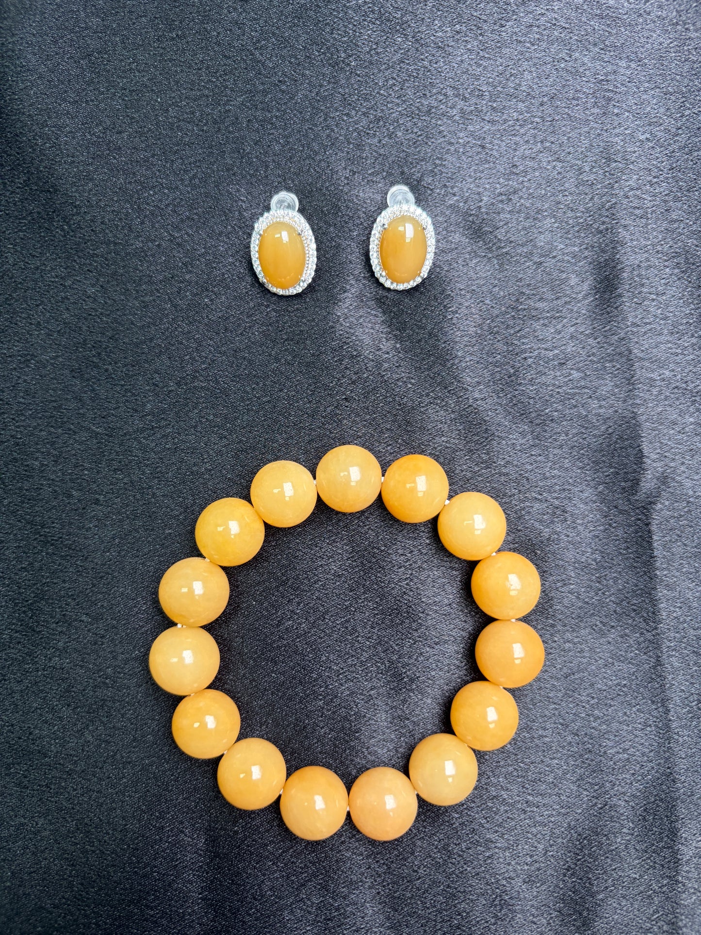 Yellow beaded bracelet and earrings on a gray fabric background
