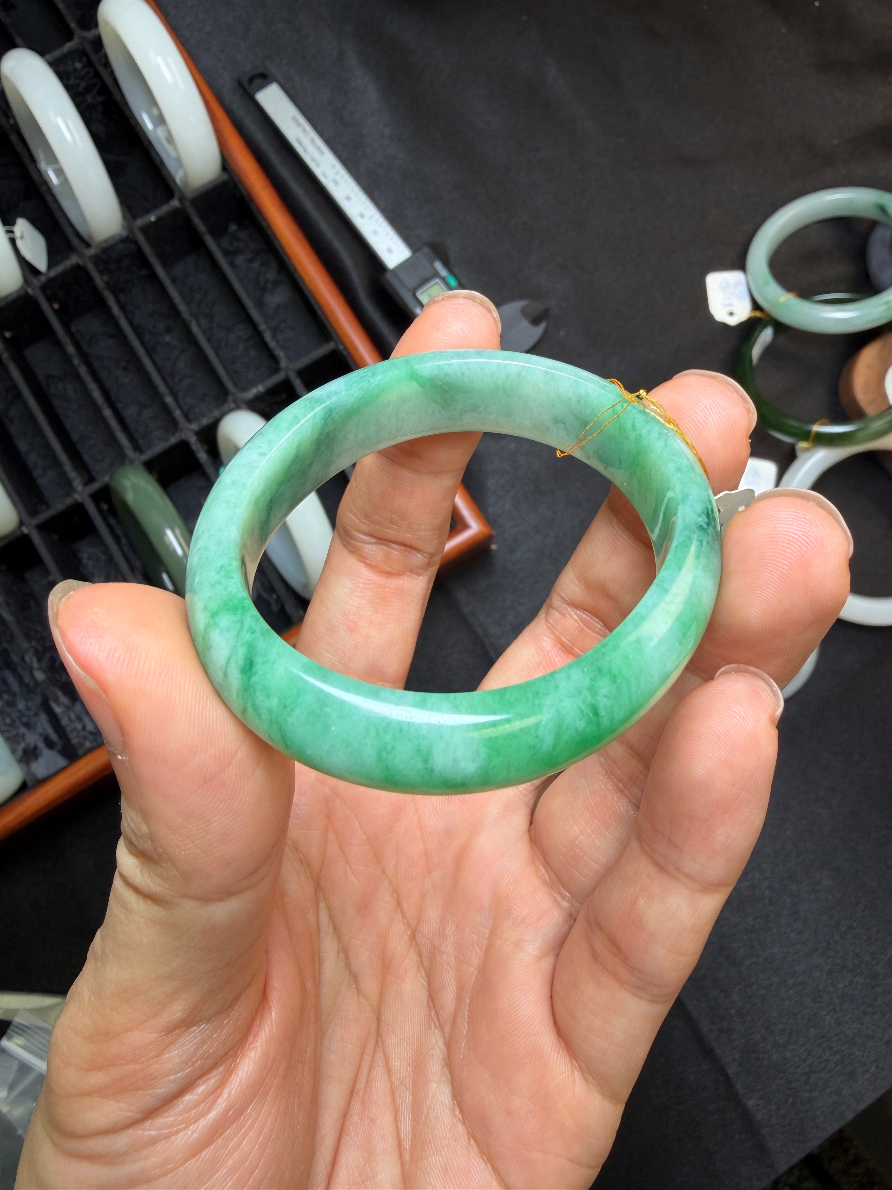 Hand holding a green jadeite bangle with blurred background
