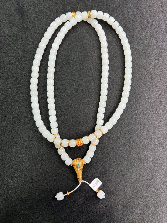 White HeTian jade beaded necklace with gold plated silver accents on a dark surface
