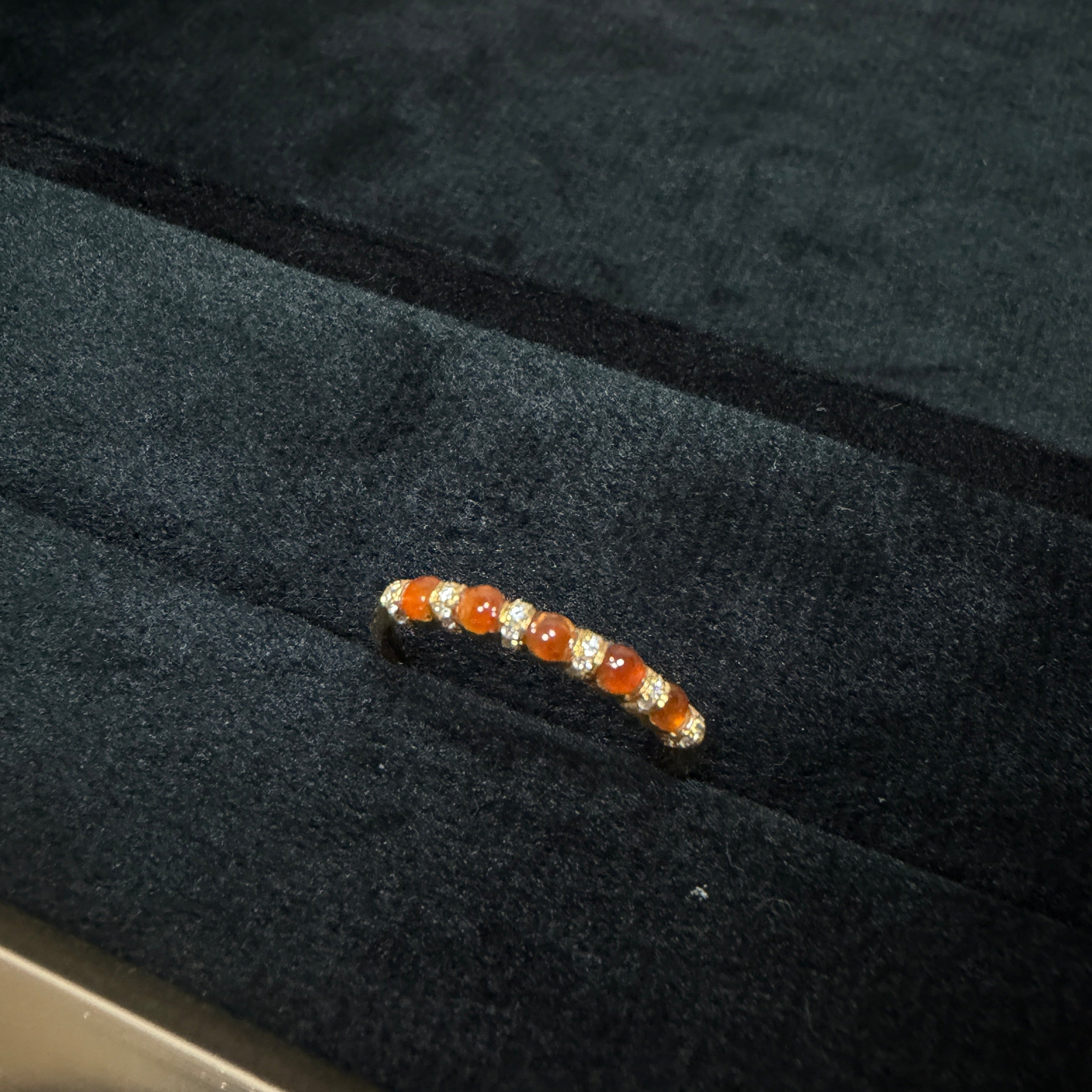 Small orange and white caterpillar on a dark surface