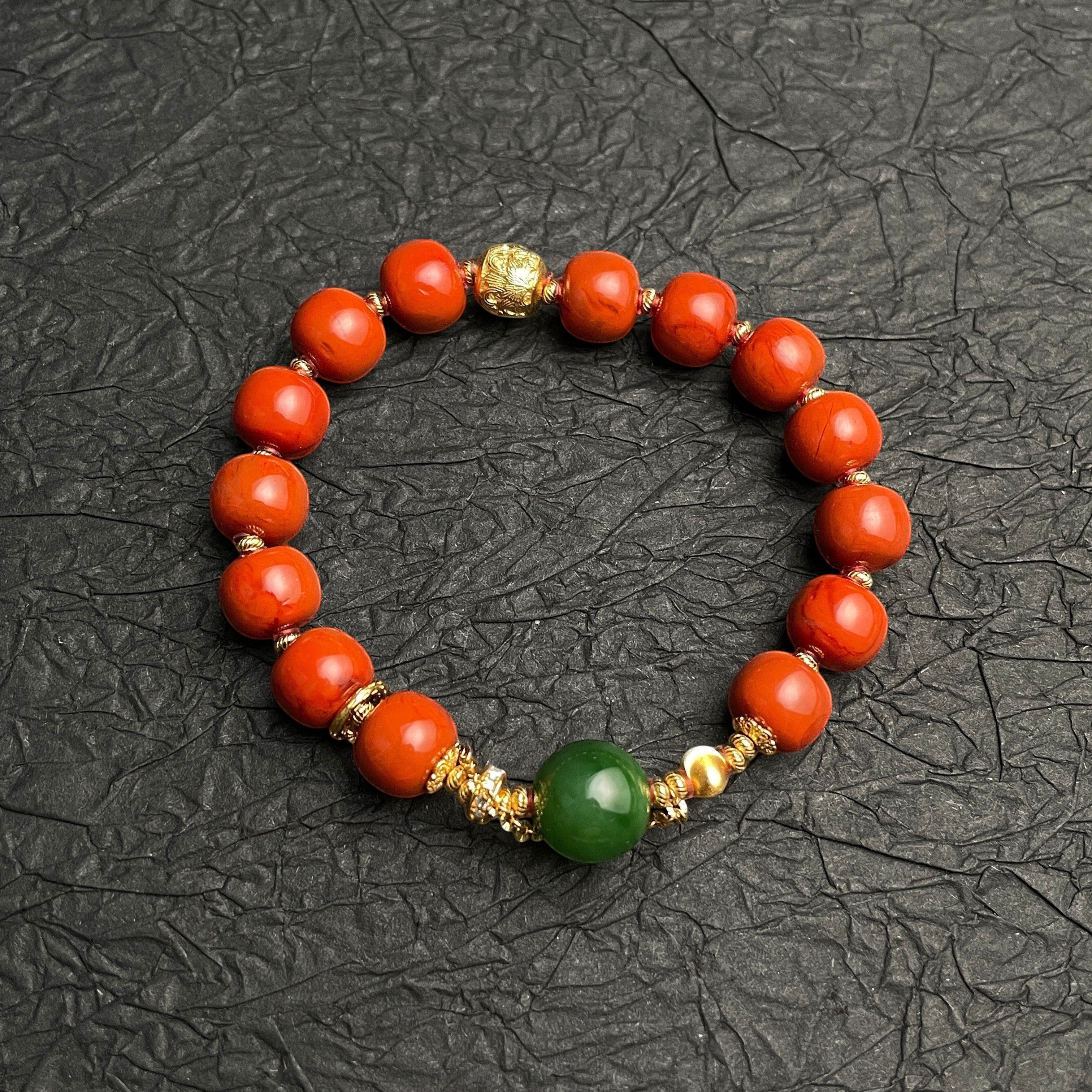 Sylvia Jewelry bracelet with vibrant red Nanhong Agate beads, a central green Hetian Jade bead, and gold-plated silver spacers.