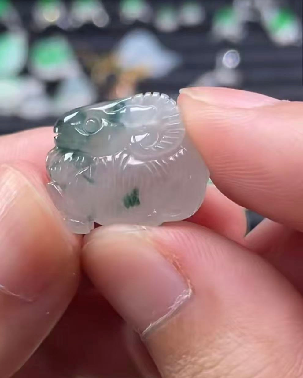 Hand holding a jade pendant with intricate carvings against a blurred background