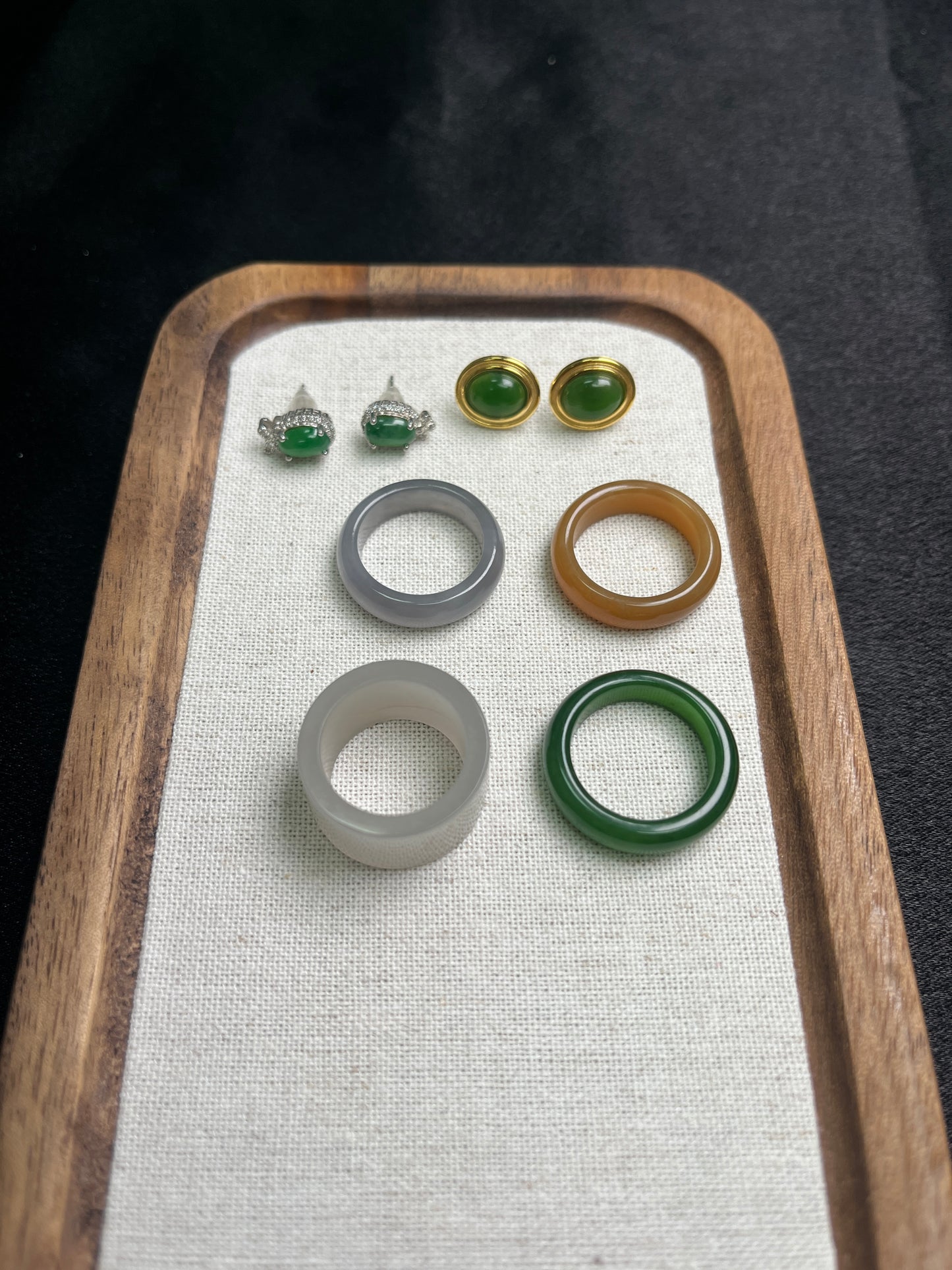 Set of jade rings on a wooden tray with a white cloth background