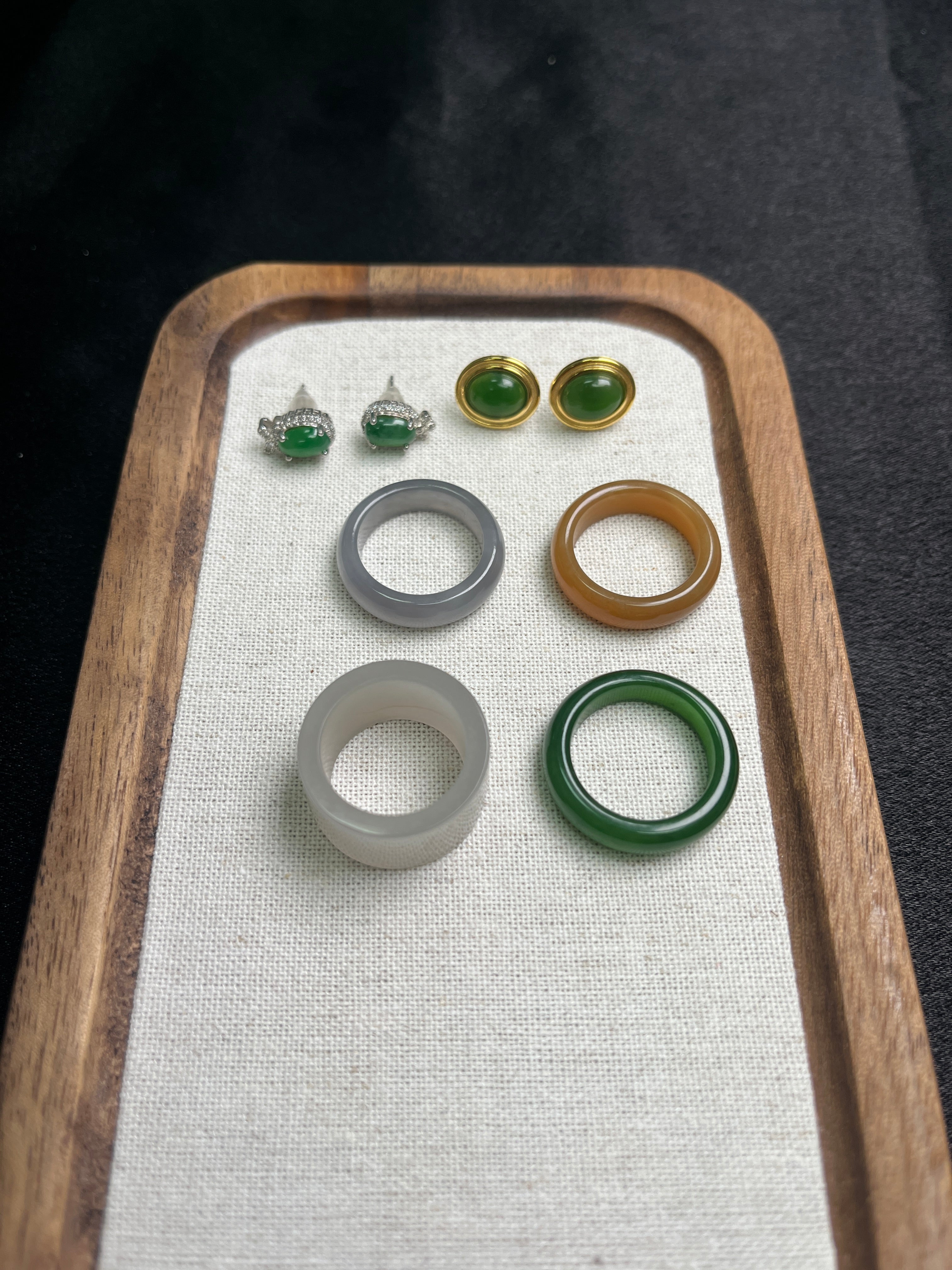 Set of jade rings on a wooden tray with a white cloth background