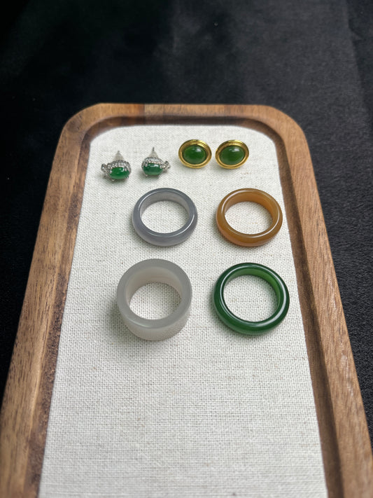 Set of jade rings on a wooden tray with a white cloth background
