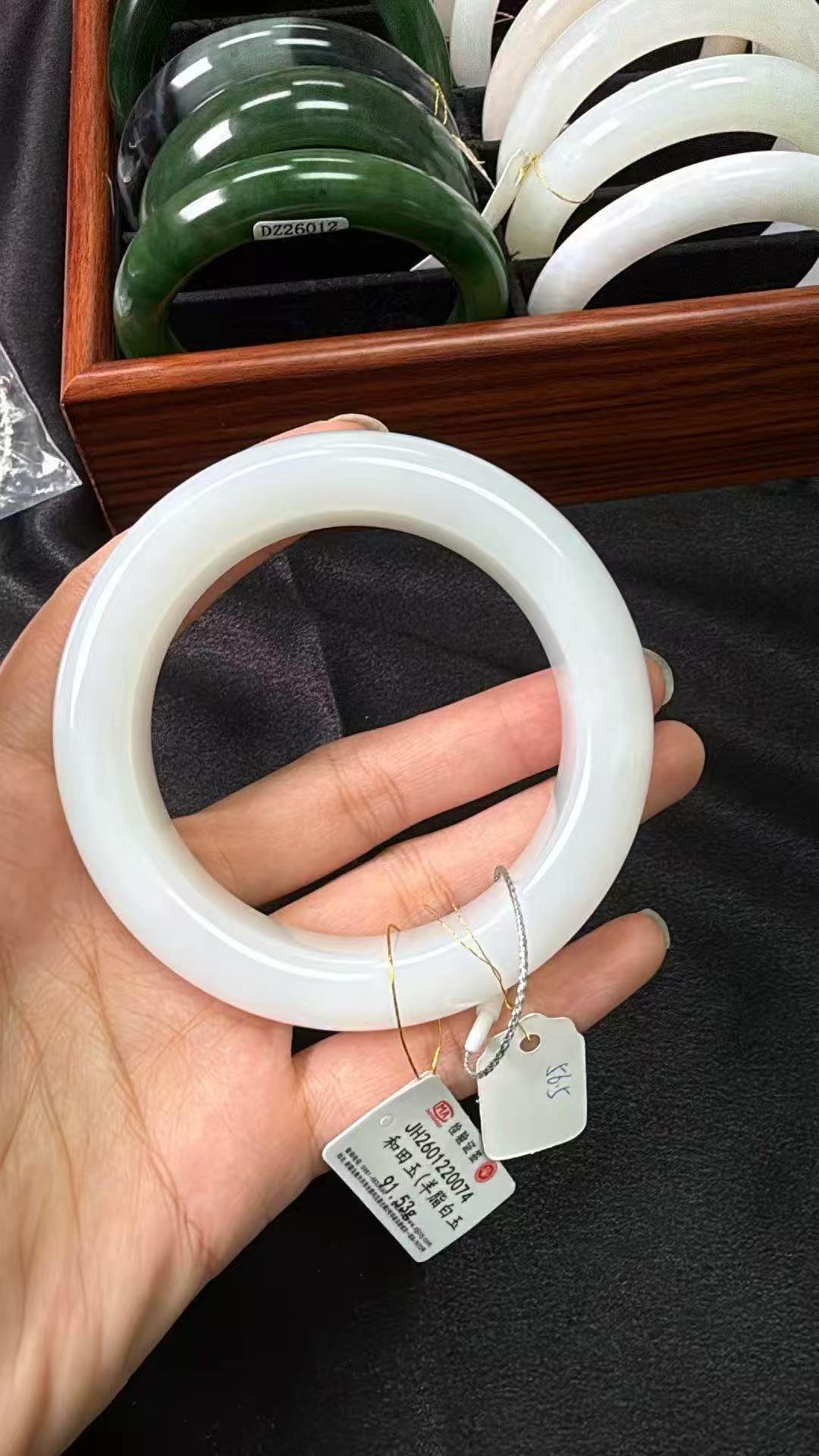 Hand holding a white jade bangle with a blurred background