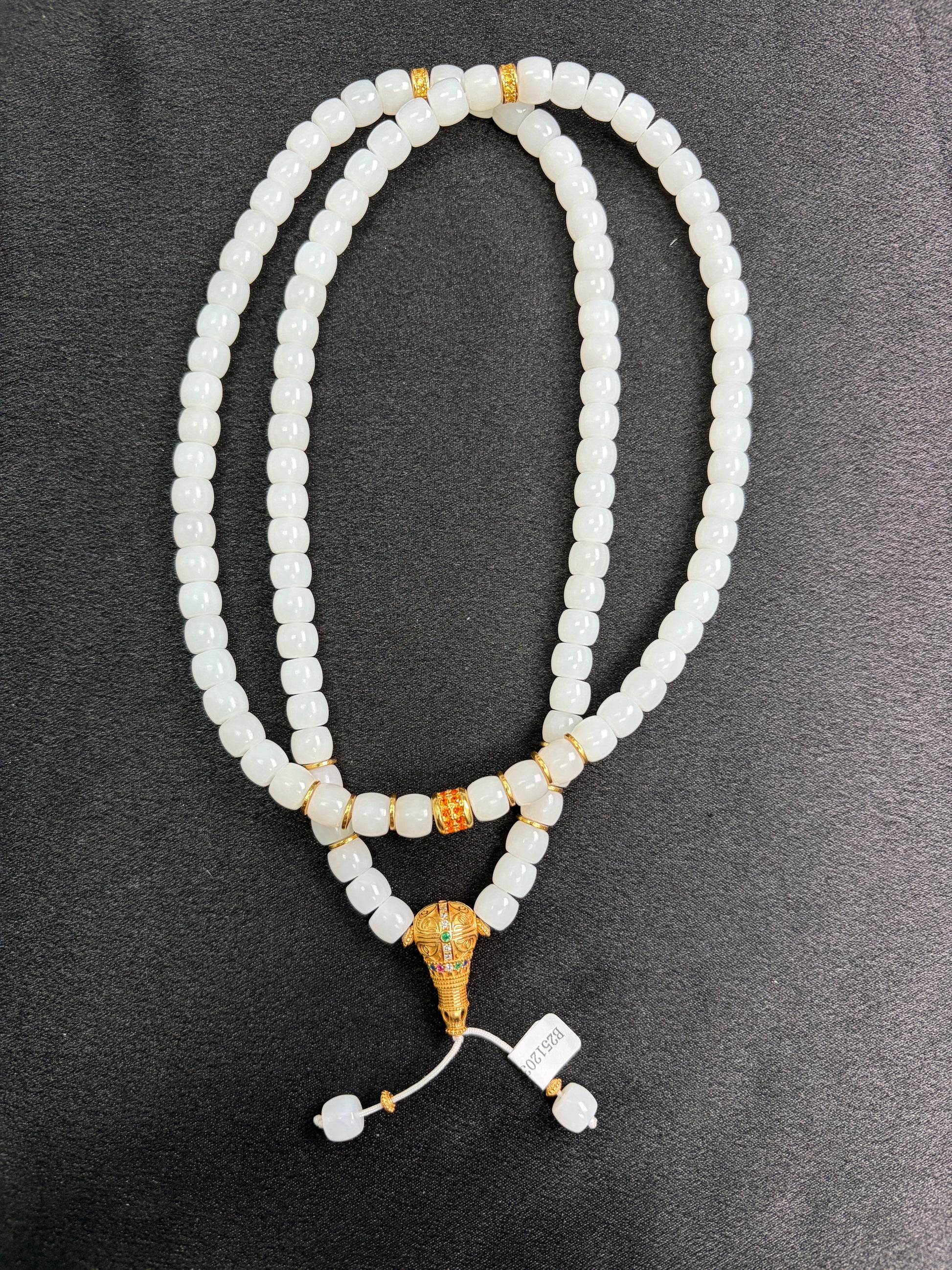 White HeTian jade beaded necklace with gold plated silver accents on a dark surface