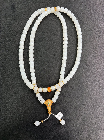 White HeTian jade beaded necklace with gold plated silver accents on a dark surface