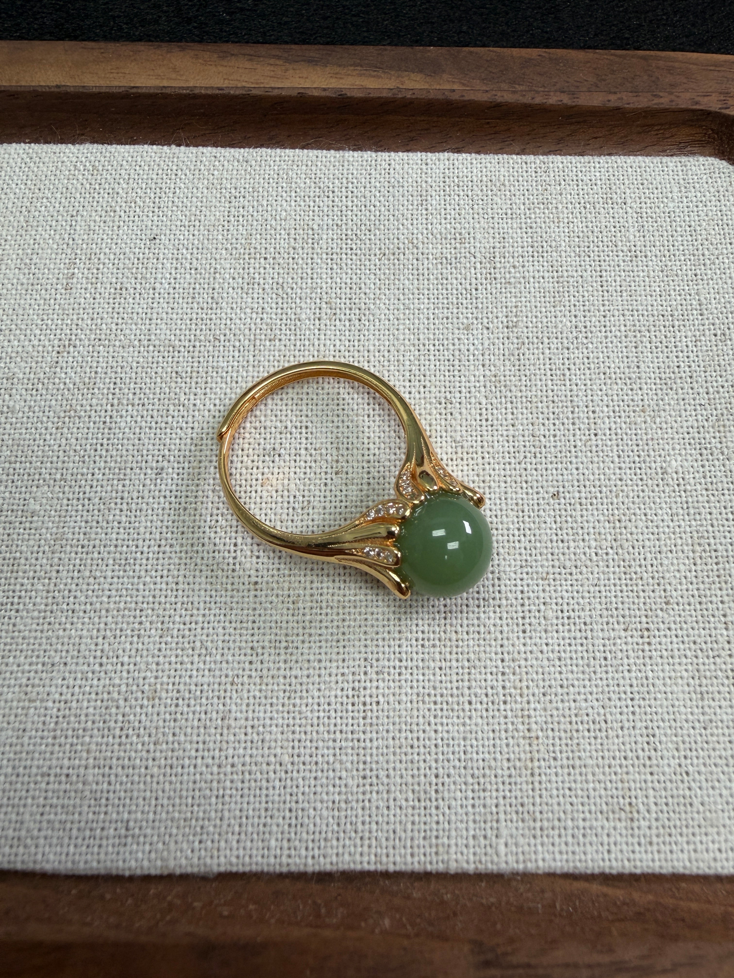 Silver ring with a green gemstone on a textured fabric background