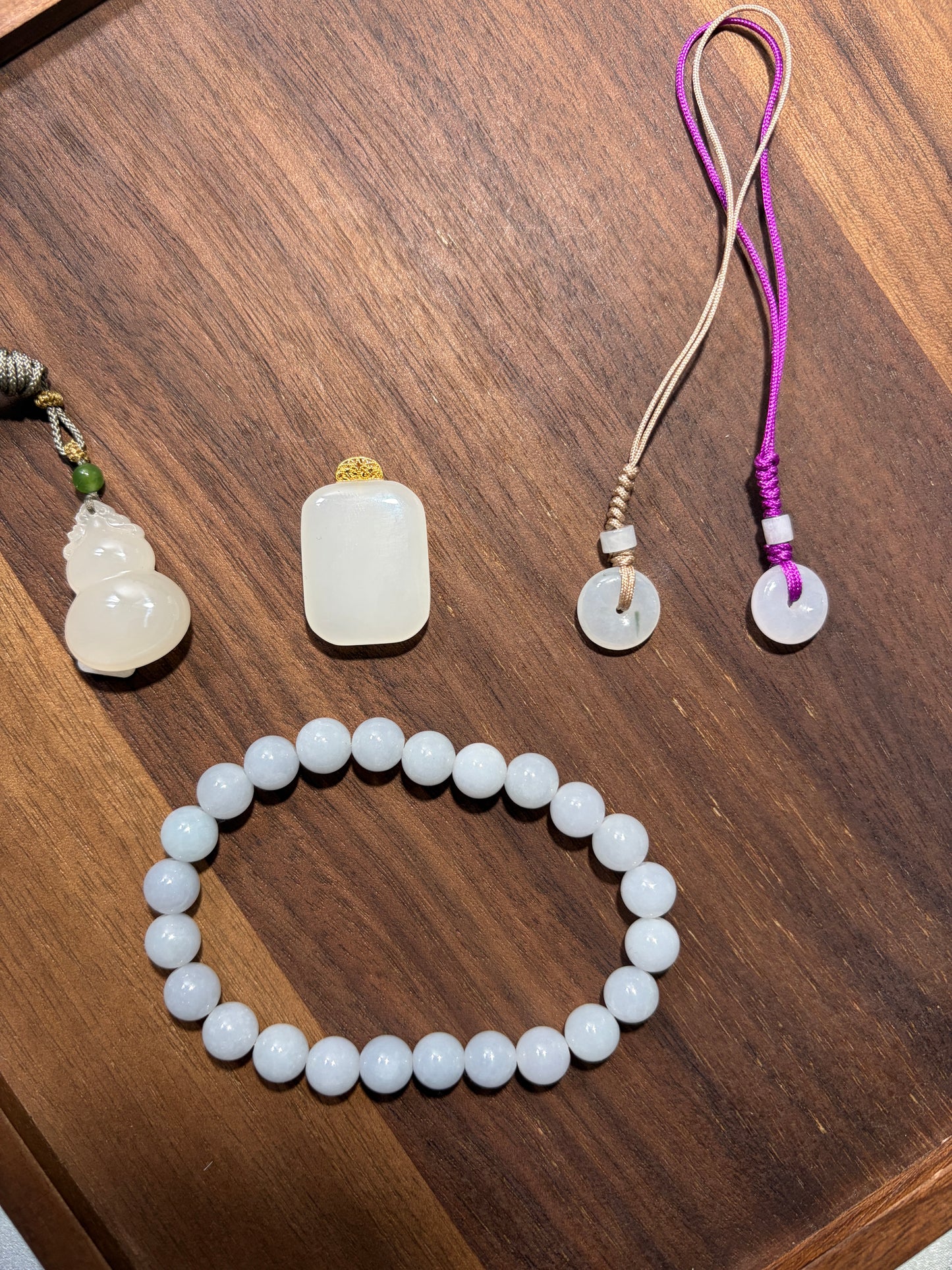 Jadeite beaded bracelet and decorative stones on a wooden surface