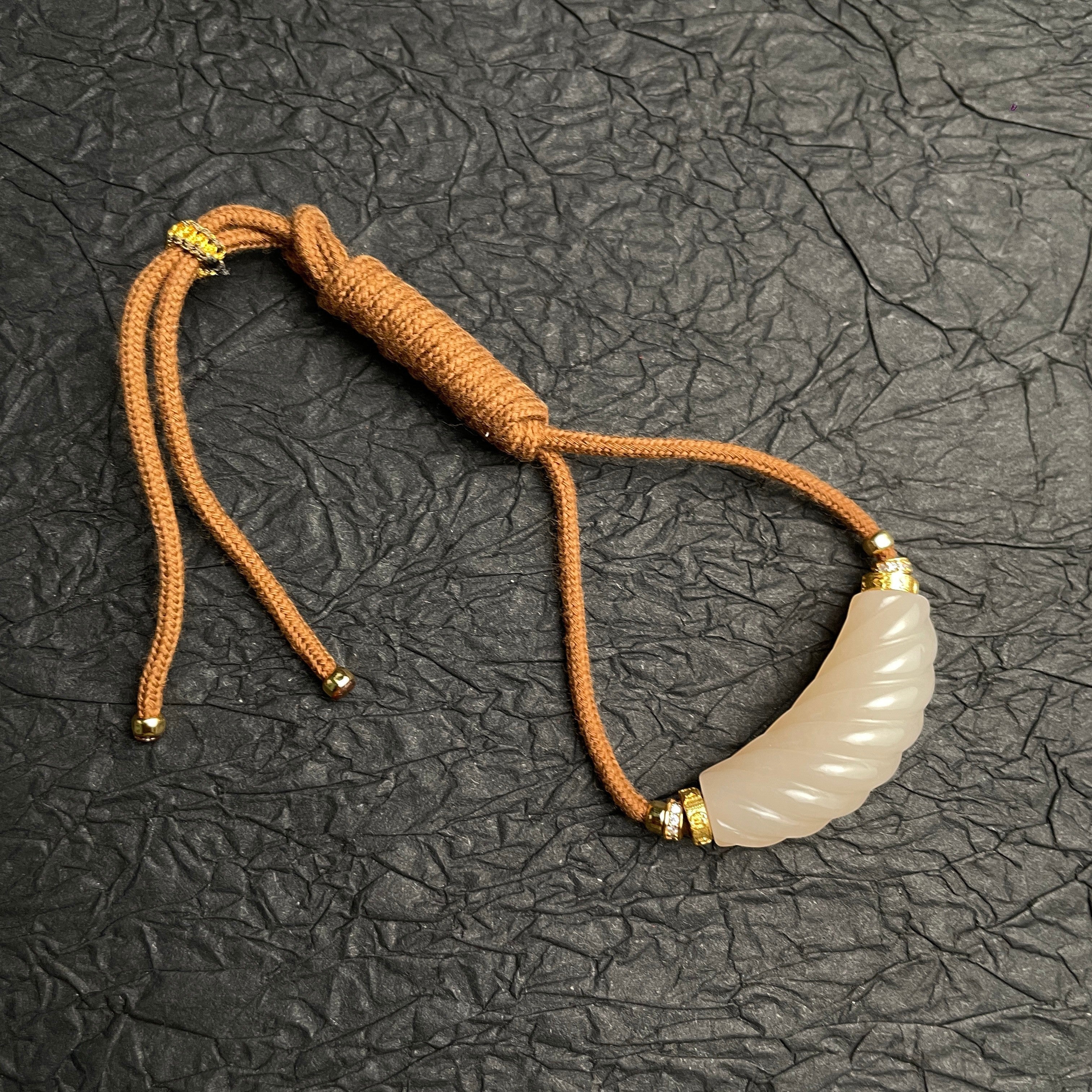Sylvia Jewelry 粉色和田玉扭转吊坠，金色镀层点缀，搭配棕色绳链。